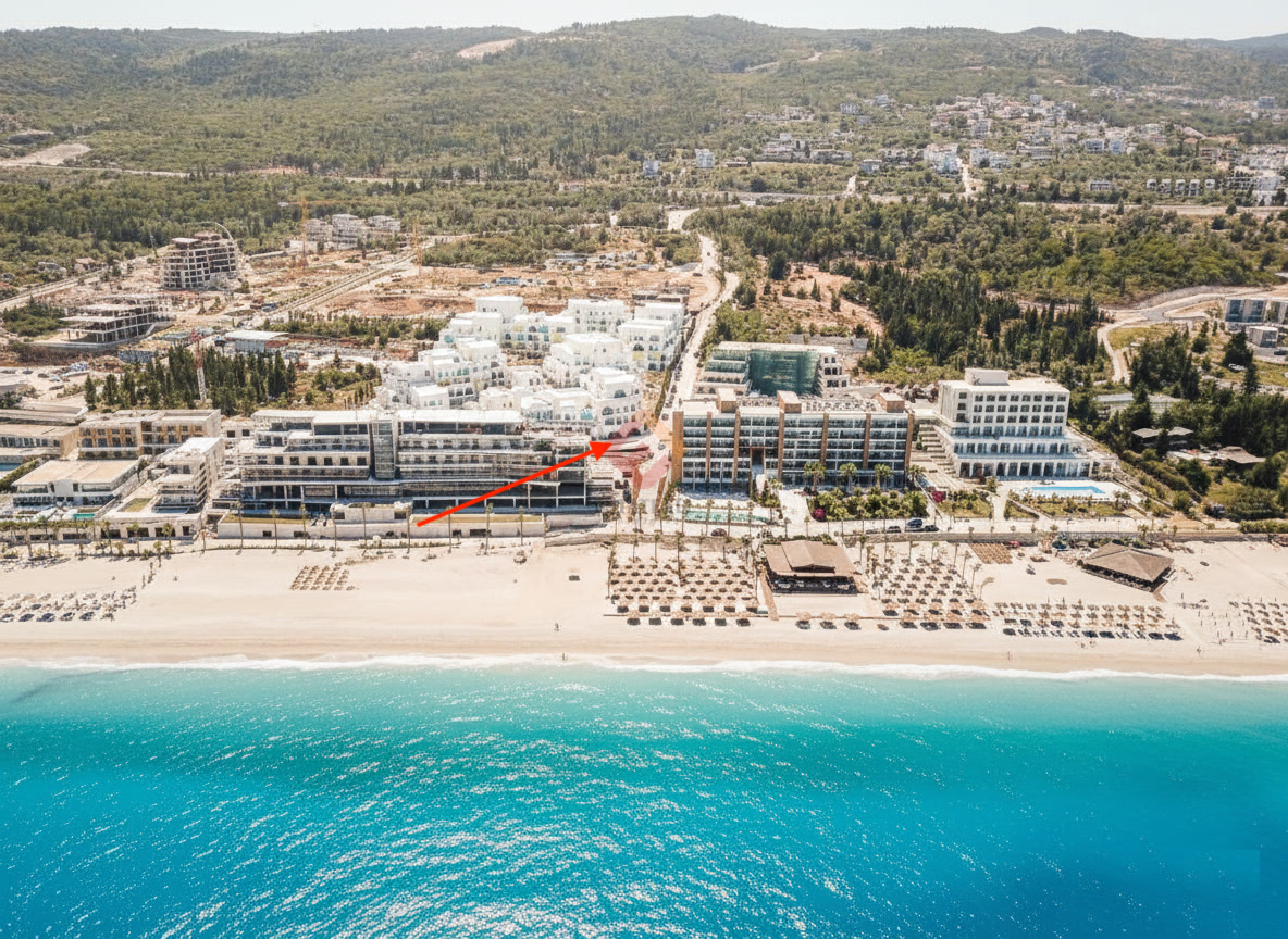 Aerial view of a beachfront resort complex under construction, with a red arrow marking one building